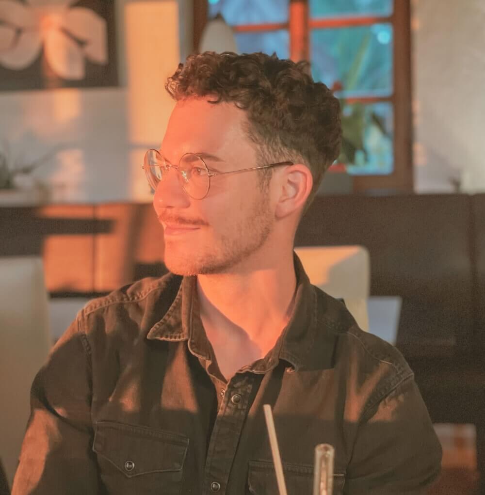 portrait of a guy inside sitting inside a restaurant with a straw in the foreground